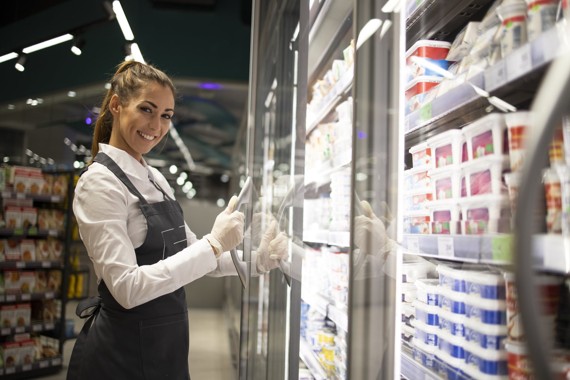 Trabajadora de supermercado junto a la nevera de bebidas